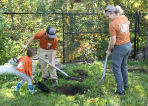 Harrison McPhee volunteers digging a hole with daughter